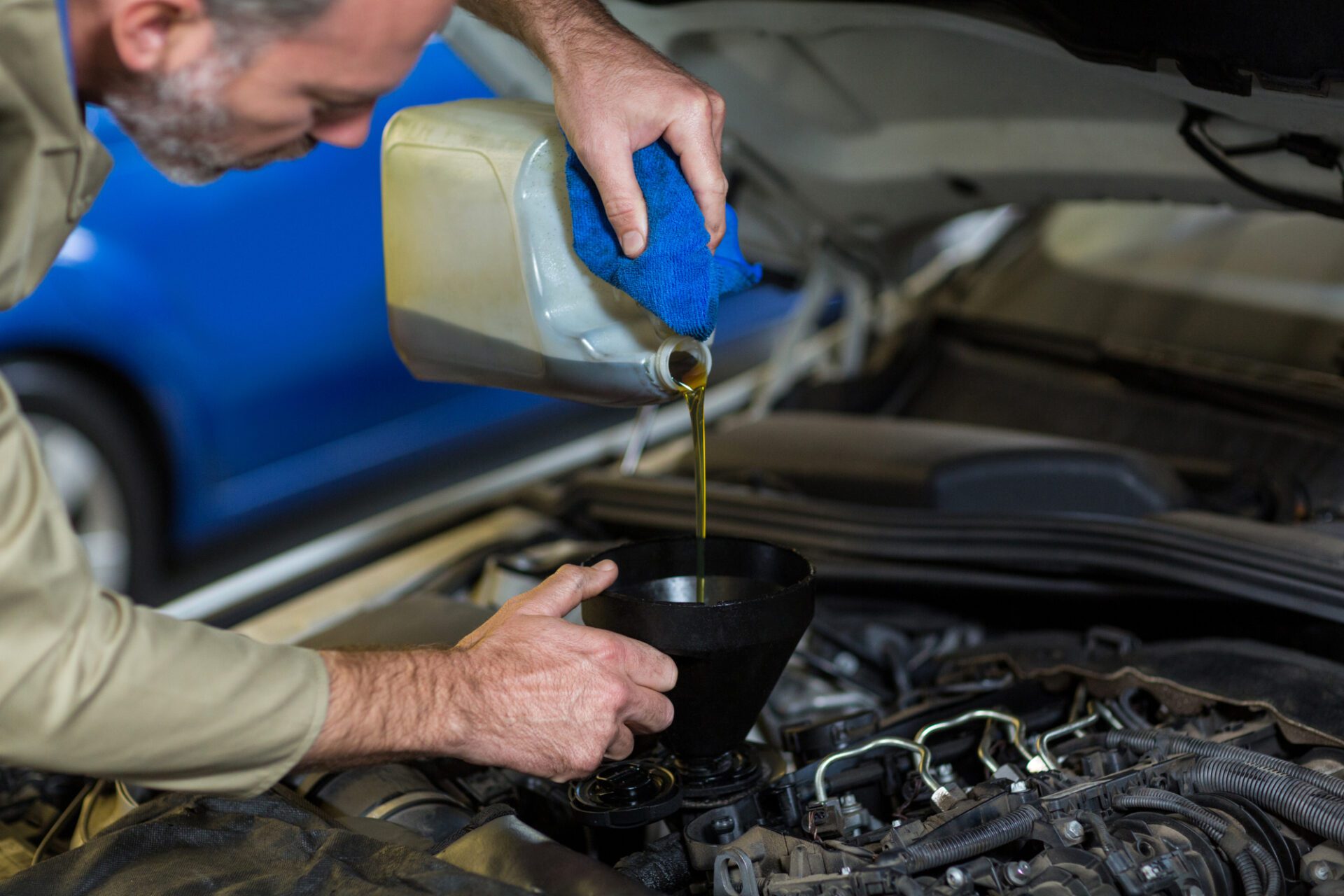 Mechanic pouring oil into car engine<br />